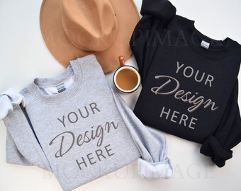 May include: Two sweatshirts, one gray and one black, laid flat on a white surface. Both sweatshirts have the text "YOUR Design HERE" printed on the front. A brown hat and a brown mug are also in the image.