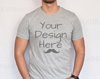 Può includere: Una maglietta grigia con il testo "Your Design Here" e un'immagine di baffi neri.