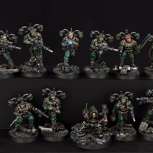 May include: A collection of miniature figurines depicting soldiers in green and camouflage uniforms, armed with rifles and other weaponry. The figurines are set on detailed, textured bases, suggesting a tabletop game or hobby.