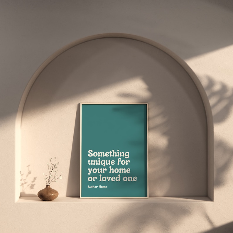 May include: A teal framed print with white text that reads "Something unique for your home or loved one" and the text "Author Name" below. The print is displayed on a shelf in a room with a light beige wall and an arched doorway.