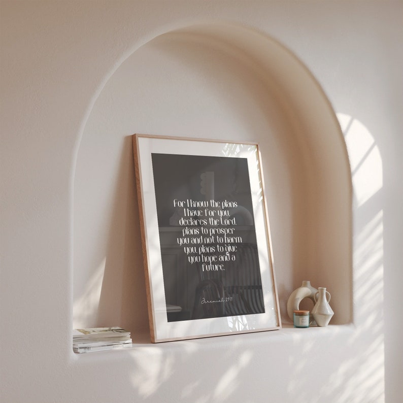 May include: A framed print with a light wood frame, featuring a black and white design with text. The text reads "For I know the plans..." and is from Jeremiah 29:11. The print is displayed on a shelf with decorative vases.
