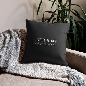 Puede incluir: Cojín negro con texto blanco que dice "Give it to God and go to sleep".