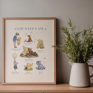 Puede incluir: Un estampado enmarcado con personajes de Winnie the Pooh y el texto "GOD SAYS I AM". Las ilustraciones incluyen a Pooh, Piglet, Tigger y Eeyore, con palabras como "Protegido", "Atesorado" y "Sabio". El marco es marr&oacute;n claro.