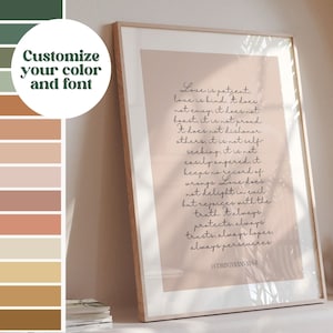 May include: A framed print with the text "Love is patient" in elegant script. The artwork has a soft pink background and a wooden frame. The image also includes a colour palette with options to customise the colour and font.