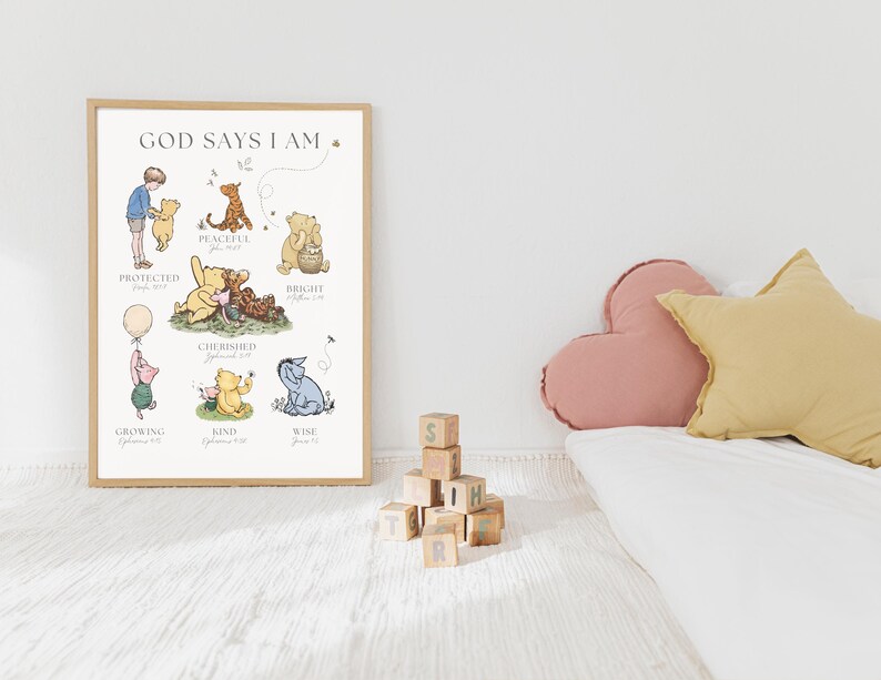 Puede incluir: Un p&oacute;ster enmarcado con el texto "GOD SAYS I AM" e ilustraciones de personajes de Winnie the Pooh. El p&oacute;ster presenta varios personajes con palabras como "Protegido" y "Amable". Una pila de bloques de madera y cojines decorativos est&aacute;n en primer plano.