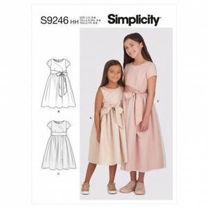 Könnte beinhalten: Simplicity Schnittmuster S9246 HH für die Größen 3-6. Die Packung zeigt Illustrationen von zwei Kleiderstilen sowie ein Foto von zwei Kleidern in Hellrosa und Champagner, jeweils mit kurzen Ärmeln, Rundhalsausschnitt und Taillenschleifen.