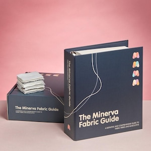 May include: A dark blue three-ring binder and matching storage box titled The Minerva Fabric Guide: A Definitive and Comprehensive Guide to Fabric Fibres and Basecloths. The set features white line graphics and a stack of fabric swatches.
