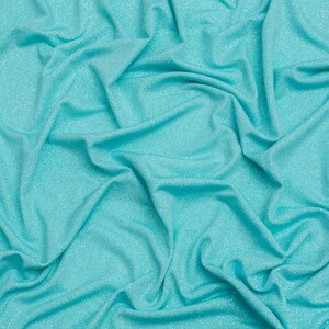 May include: A vibrant turquoise fabric featuring a subtle, fine glitter finish throughout the material. The textile is arranged in soft, flowing folds and deep drapes, creating a textured surface with varying light and shadow across the surface.