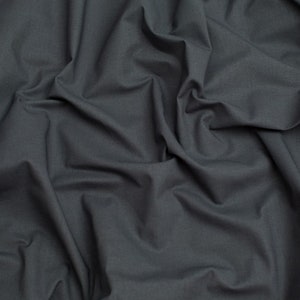 Puede incluir: Primer plano de una tela gris oscuro con una textura lisa. La tela está doblada y drapeada, creando pliegues y arrugas suaves.