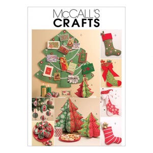 Op de afbeelding: McCall's Crafts naaipatroon-envelop met instructies voor stoffen kerstbomen, kousen en ornamenten. De omslag toont een groene kerstboom voor aan de muur, diverse kousen met patronen en gevulde stoffen boomdecoraties.