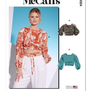 Op de afbeelding: McCall's M8324 naaipatroon-envelop met een cropped top met lange mouwen en een strikdetail in de taille in een roestoranje en witte bladprint. Bevat technische illustraties voor variaties A en C, met een bedrukte en een effen groenblauwe top.