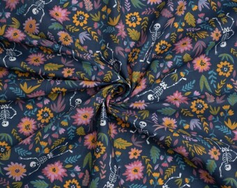 May include: A dark blue fabric featuring a repeating pattern of white skeletons interspersed with pink and orange flowers, along with green and yellow leaves. The material is gathered in the center, creating folds that highlight the printed design.