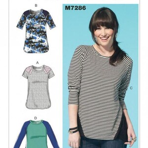 May include: McCall's M7286 sewing pattern envelope featuring illustrations of four shirt variations: a blue camo print, a grey top with pink accents, a green and blue long-sleeve shirt, and a black and white striped long-sleeve shirt.