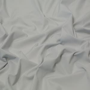 May include: A close-up of a smooth, light grey fabric with soft folds and wrinkles.