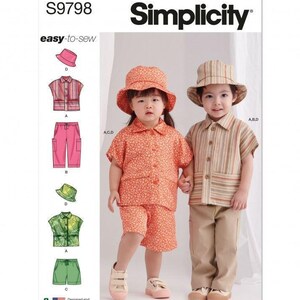 May include: Simplicity sewing pattern S9798 for children's clothing. The pattern includes designs for a bucket hat, a short-sleeved button-down shirt, and shorts or trousers. Illustrations show variations in floral, striped, and solid green fabric patterns.