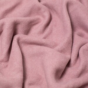 Puede incluir: Primer plano de una tela suave y rosa con una textura lisa. La tela está doblada y drapeada, creando un aspecto suave y acogedor.