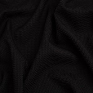 Op de afbeelding: Zwarte, gestructureerde stof met een gerimpelde, gekreukelde uitstraling. De stof heeft een subtiele glans en een zachte, gladde textuur.