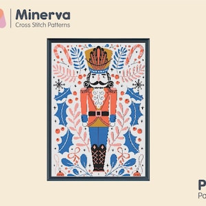 Puede incluir: Un patrón de punto de cruz con un cascanueces colorido con una chaqueta roja, pantalones azules y un sombrero dorado. El cascanueces está rodeado de acebo, bastones de caramelo y otros detalles festivos.