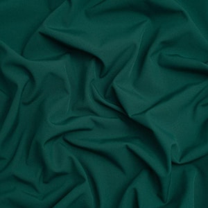 May include: A solid dark forest green fabric with a smooth, matte texture. The material is arranged in soft, flowing folds and deep creases that create a dynamic play of light and shadow across the surface, highlighting the consistent color.