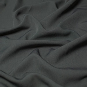 May include: Close-up of a dark gray fabric with soft, flowing folds and wrinkles.
