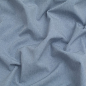 Puede incluir: Primer plano de una tela azul claro con una superficie texturizada. La tela está arrugada y doblada, mostrando su textura suave y fluida.