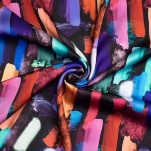 Pode incluir: Tecido abstrato colorido com fundo preto. O tecido tem um acabamento acetinado e apresenta um padrão repetitivo de pinceladas verticais em várias cores, incluindo laranja, rosa, azul, roxo e verde.