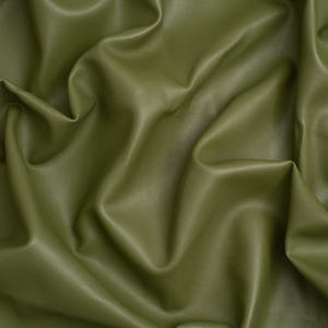 Pode incluir: Um tecido verde-oliva sólido com um acabamento liso e mate e uma textura macia e flexível. O material está drapeado em dobras profundas e fluidas que criam uma série de luzes e sombras na superfície, enfatizando a natureza flexível do tecido.