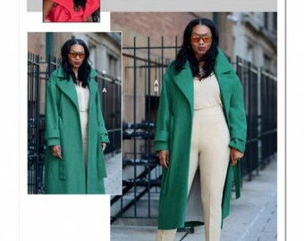 Può includere: Una busta per cartamodello etichettata ME2001 Know Me by Mimi G che presenta un cappotto verde a maniche lunghe con colletto ampio e cintura, indossato sopra una camicia beige abbottonata e pantaloni beige. Il cartamodello include immagini del cappotto.