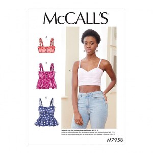 May include: McCall's M7958 sewing pattern envelope featuring illustrations of four crop top variations labeled A, B, C, and D. The designs include scalloped straps, button details, and peplum hems in red, pink, and blue star or gingham prints.