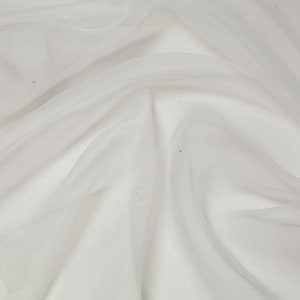 Puede incluir: Tela blanca transparente con un brillo sutil. La tela está drapeada y doblada, mostrando su textura y caída.