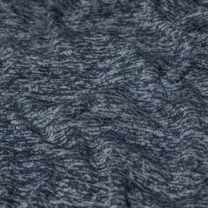 Pode incluir: Close-up de um tecido texturizado azul e cinza com um padrão sutil. O tecido é macio e tem uma sensação ligeiramente elástica.