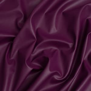 May include: Close-up of a deep purple fabric with a smooth, satiny texture. The fabric is draped and folded, creating soft, flowing lines.