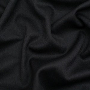 May include: Close-up of a black fabric with a smooth, textured surface. The fabric is wrinkled and folded, creating a dramatic and abstract pattern.