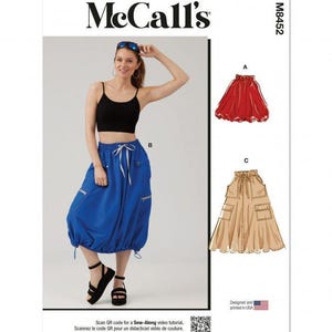 Op de afbeelding: McCall's M8452 naaipatroon-envelop met een zwarte crop top en een blauwe midirok met een taille met trekkoord, zijzakken en een geplooide zoom. Bevat illustraties voor een rode rok en een beige rok met zakken en een trekkoord.