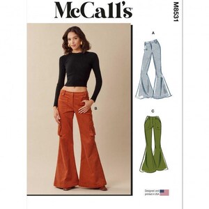 Op de afbeelding: McCall's M8531 naaipatroon-envelop met een zwart shirt met lange mouwen en een roestkleurige corduroy cargobroek met uitlopende pijpen. De illustratie toont varianten A en C van de broek in lichtblauwe denim en olijfgroene stof.