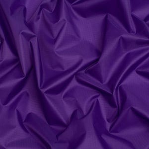 May include: A deep purple fabric featuring a subtle grid-like ripstop texture. The material is draped in soft, flowing folds, creating a series of highlights and shadows across the surface that emphasize the vibrant, solid violet color throughout.