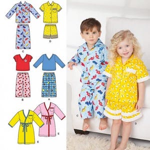 Può includere: Modello di cucito Simplicity numero 1574 per pigiami e accappatoio per bambini. Il modello include una varietà di stili, tra cui una parte superiore a maniche corte con colletto, pantaloni lunghi e un accappatoio con cintura da legare. Il modello è illustrato con un bambino e una bambina che indossano il pigiama e l'accappatoio.