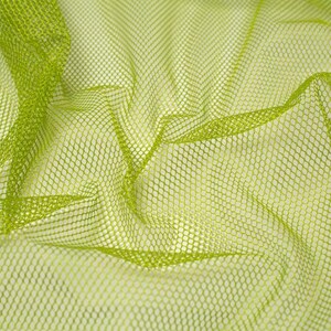 Op de afbeelding: Een fel limoengroene mesh-stof met een consistent zeshoekig rasterpatroon. Het materiaal is gedrapeerd om zachte plooien en rondingen te creëren, wat de semi-transparante aard van het net en de uniforme structuur van het weefsel benadrukt.