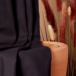 May include: Black fabric draped over a terracotta pot with dried grasses. The fabric has a soft, textured look.