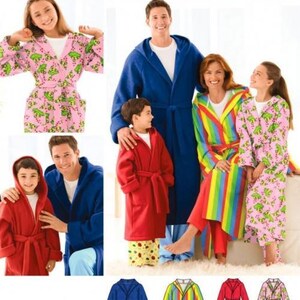 May include: Simplicity 3575 easy-to-sew sewing pattern for hooded robes. The pattern includes designs for a solid blue robe, a solid red robe, a rainbow striped robe, and a pink robe with a green frog print, all featuring tie belts.