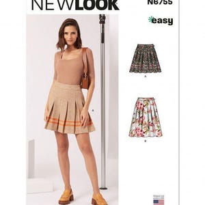 May include: New Look sewing pattern N6755 for a pleated skirt. The envelope features a model wearing a tan plaid skirt with orange stripes, alongside illustrations of two skirt variations: one with a dark floral print and one with a light floral print.