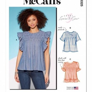 May include: McCall's M8325 sewing pattern. The image shows a woman in a blue dotted top with frilled sleeves. The pattern includes illustrations of different top styles and the text "Learn to Sew". Designed and printed in the USA.