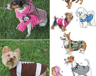 May include: Simplicity 1239 sewing pattern for dog clothing. The cover features photographs and illustrations of various dog breeds wearing coats, vests, and a scarf. Designs include a football-themed coat, a camouflage vest, and a pink patterned coat.