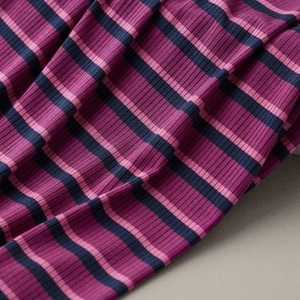 May include: A ribbed fabric featuring a repeating pattern of horizontal stripes in shades of dark navy blue, vibrant magenta, and soft light pink. The material has a distinct vertical texture created by the fine, raised ribbing across the surface.