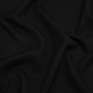 Op de afbeelding: Een close-up van zwarte stof met zachte plooien en een subtiele textuur. Het materiaal lijkt gedrapeerd, waardoor schaduwen en highlights ontstaan die de diepte en beweging van de stof benadrukken. De algehele indruk is glad en elegant.