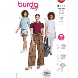 May include: A Burda Easy 5809 sewing pattern envelope featuring three shirt variations. The designs include a light blue shirt, a maroon shirt, and a white shirt, all with short puff sleeves. The text includes Burda easy, 5809, and Jersey Knits.