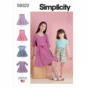 May include: Simplicity sewing pattern S9322 featuring illustrations of four dress variations. The pattern displays two dresses worn by models: one in a magenta floral print with three-quarter sleeves and one with a teal striped top and floral skirt.