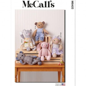 Peut inclure: Pochette de patron de couture McCall's M8422 illustrant cinq peluches : un ours brun en salopette bleue, une souris grise en robe fleurie, un lapin rose, un ours à carreaux et un lapin portant une robe à carreaux violets.