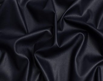 May include: A dark navy blue fabric with a smooth, matte finish and a fine-grained texture. The material is draped in soft, deep folds that create a series of highlights and shadows across the surface, emphasizing the flexible nature of the textile.