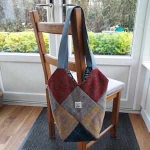 May include: A patchwork tote bag with a blue, red, and brown colour scheme. The bag has a light grey tweed fabric with a diamond pattern. The bag is made of a soft, textured fabric.